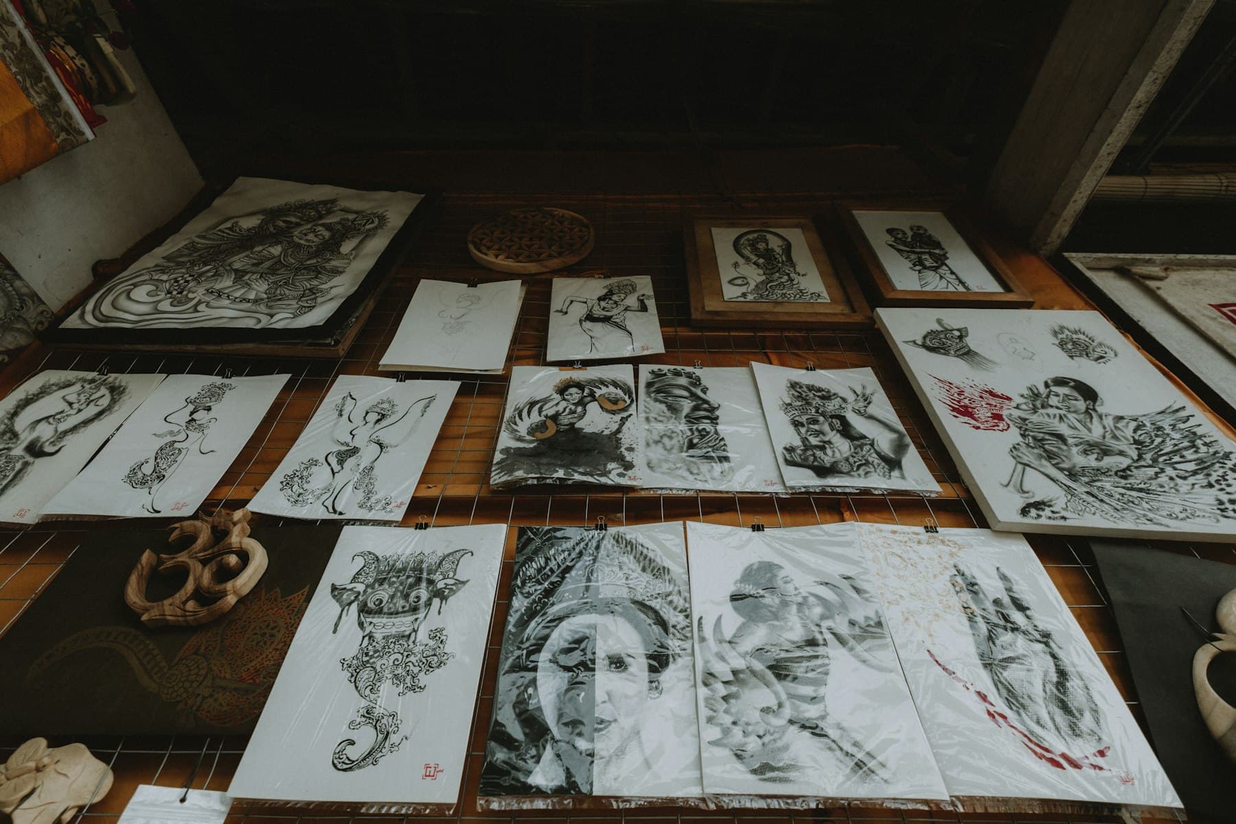 Des planches de flashs dessinées à l'encre, étalées sur un établi de bois.
